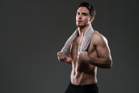 Image of handsome athlete standing in gym over grey background holding towel.の写真素材
