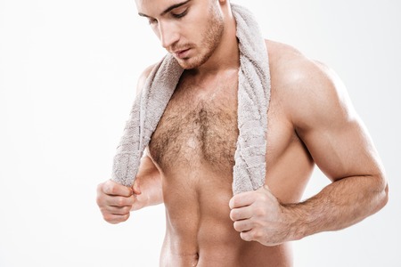 Picture of strong sportsman standing with towel over white background. Look aside.の写真素材