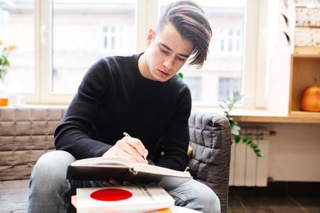Picture of serious caucasian student in library learning education material with books. Look at...