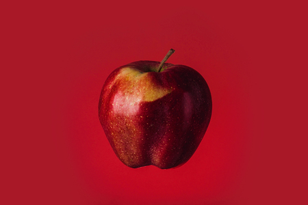 Shiny red apple isolated on a red backgroundの写真素材