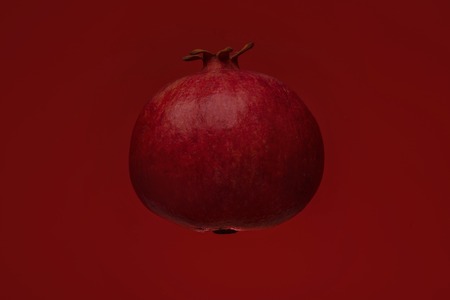 Ripe pomegranate fruit isolated on red backgroundの写真素材