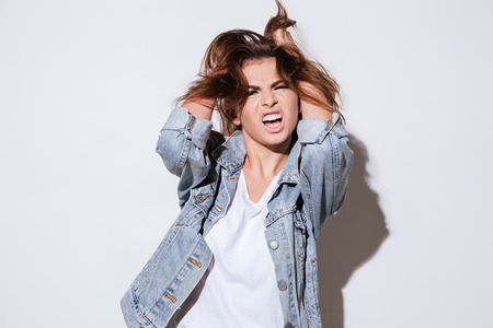 Image of a stressed woman dressed in jeans jacket standing isolated on a white background. Look at camera.の写真素材