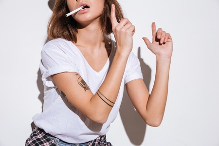 Cropped photo of lady dressed in white t-shirt standing isolated over white background with cigarette.の写真素材
