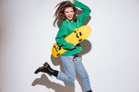 Picture of screaming skater woman dressed in green sweater isolated over white background with...