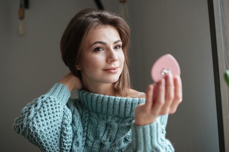 Photo of gorgeous cute lady sitting at the table in cafe and looking at mirror.の写真素材