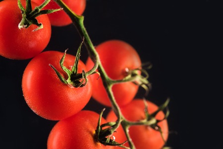 Ripe fresh cherry tomatoes isolated on black backgroundの写真素材