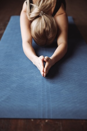 Closeup of sportswoman practicing yoga on mat on the floorの写真素材