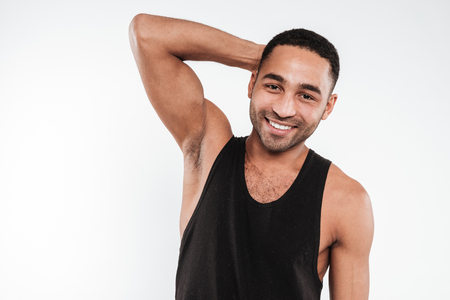 Photo of smiling young dark skinned man wearing black clothes posing over white background and looking at camera.の写真素材
