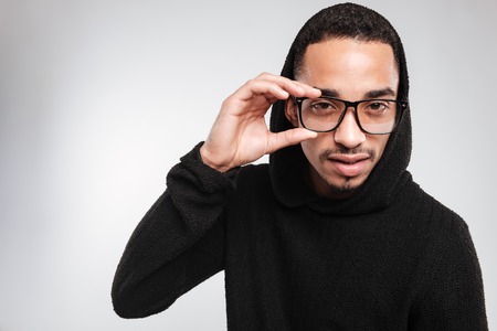 Portrait of handsome african american young man in glasses and black hoodieの写真素材