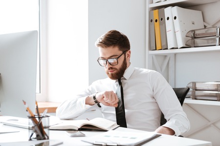 Image of handsome businessman sitting in office while looking at watch.の写真素材