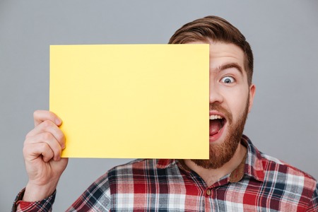 Photo of happy shocked young bearded man holding copyspace blank standing over grey background.の写真素材