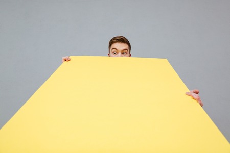Photo of shocked bearded man holding copyspace board standing over grey background.の写真素材