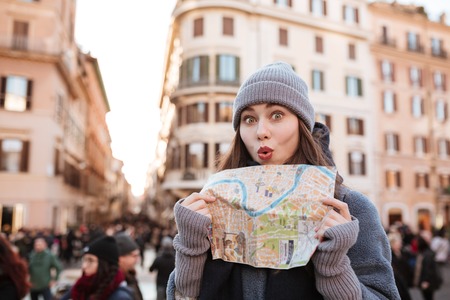 Funny playful young woman using map and having fun in the cityの写真素材