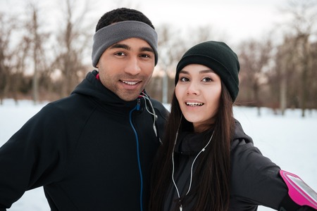 Portrait of a smiling happy multiracial fitness couple outdoors in winterの写真素材