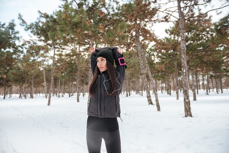 Fitness woman doing stretching exercises before running outdoors in winterの写真素材