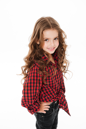Happy cute little girl in plaid shirt standing and posing over white backgroundの写真素材