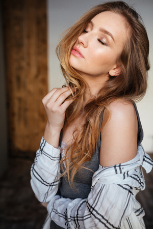 Picture of young gorgeous woman posing indoors dressed in lingerie and shirt. Eyes closed.の写真素材