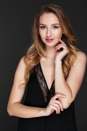 Photo of attractive young lady standing and posing over grey background. Look at camera.の写真素材
