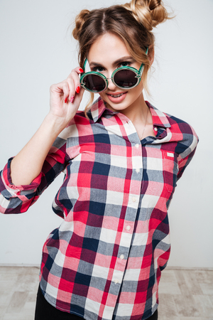 Verical portrait of Woman in shirt and sunglasses looking at camera. Isolated gray backgroundの写真素材