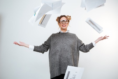 Tired stressed young woman in glasses throwing documents in the airの写真素材