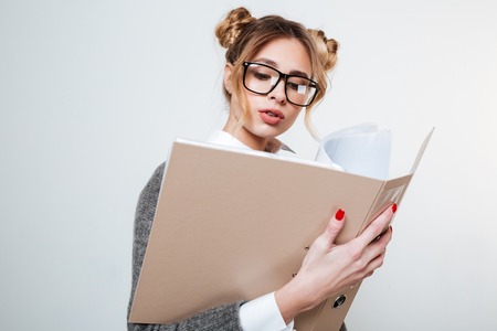 Concentrated beautiful young woman in glasses holding folder with documentsの写真素材
