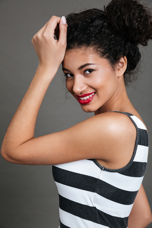 Cheerful charming african american young woman with red lips over grey backgroundの写真素材