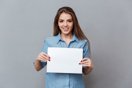 Woman in shirt showing blank board in studio. Isolated gray background