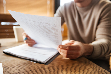 Cropped photo of attractive young man in office working with documents. Coworking.の写真素材