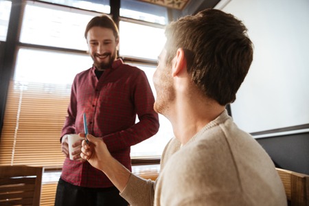 Image of two happy young colleagues in office talking with each other. Coworking.の写真素材