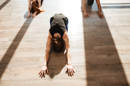 Top view of group of people practicing yoga on wooden floor in studioの写真素材