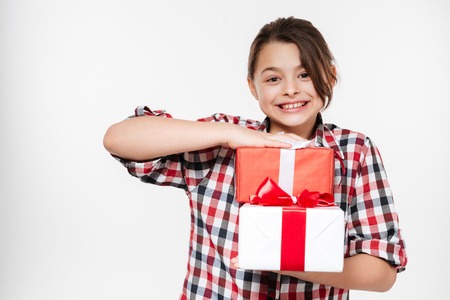 Smiling Girl in shirt with gifts in hands looking at camera. Isolated gray backgroundの写真素材