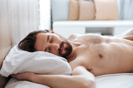 Attractive bearded young man sleeping in bed at homeの写真素材