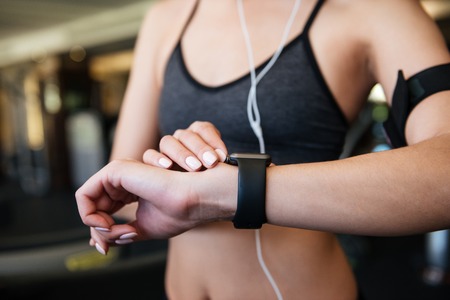 Cropped photo of young sports woman make sport exercises indoors at gym while listening music while...