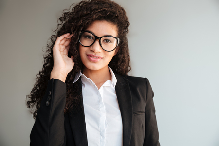 Image of incredible african business lady wearing glasses standing over grey background. Looking at camera.の写真素材