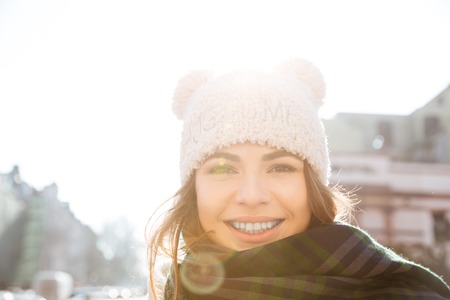 Image of happy young woman walking on the street wearing hat and scarf.の写真素材