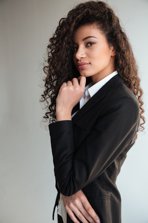 Picture of incredible african business lady standing over grey background. Looking at camera.の写真素材