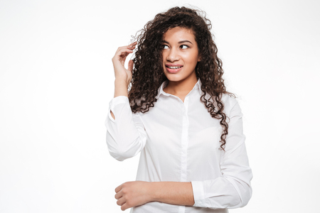 Image of pretty young curly african woman standing and posing over white background. Looking aside.の写真素材