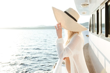 Image of young attractive beautiful woman wearing hat posing on the yachtの写真素材