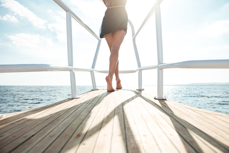 Cropped back view photo of young amazing girl standing on the yachtの写真素材