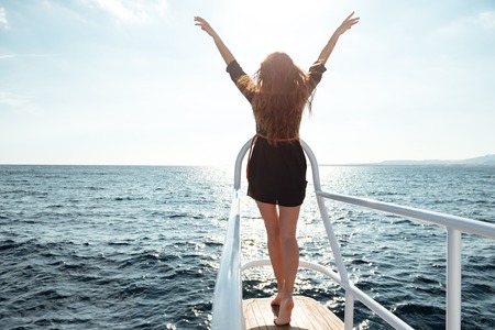 Back view image of young amazing woman standing on the yachtの写真素材