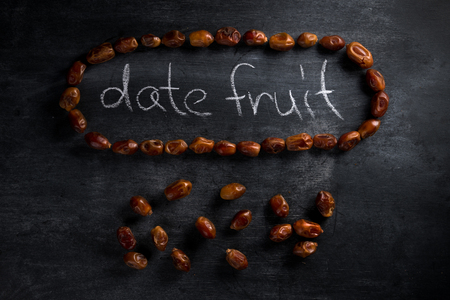 Top view picture of date fruit over dark chalkboard background