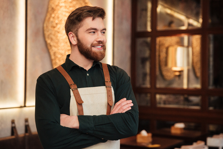 Photo of handsome young man waiter standing in cafe. Looking aside.の写真素材