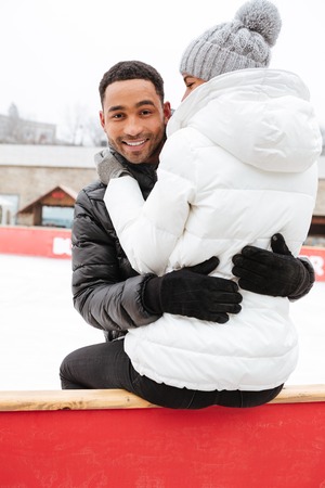 Image of young happy loving couple skating at ice rink outdoors. Man looking at camera.の写真素材