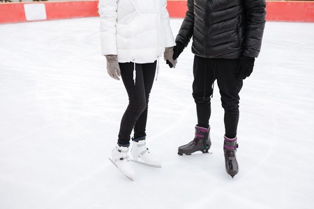 Cropped image of young loving couple skating at ice rink outdoors.の写真素材
