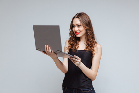 Smiling Woman using laptop in studio over gray backgroundの写真素材