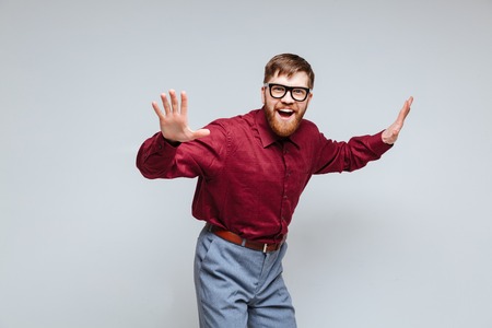 Happy Male nerd in eyeglasses which dancing in studio. Isolated gray backgroundの写真素材