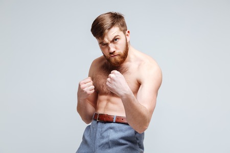 Serious Male nerd as fighter with naked torso. Isolated gray backgroundの写真素材