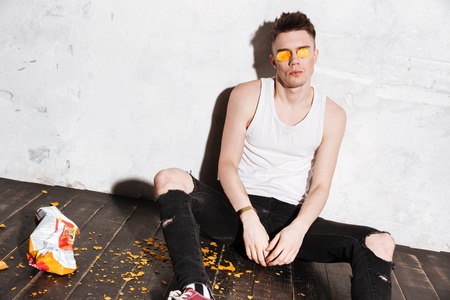 Hipster sitting on the floor and having fun over gray backgroundの写真素材