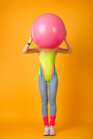 Picture of attractive young sports woman posing over yellow background with fitness ball.の写真素材