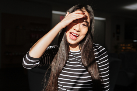 Asian woman in sweater with open mouth which posing in cafeteria and covering from the sunの写真素材